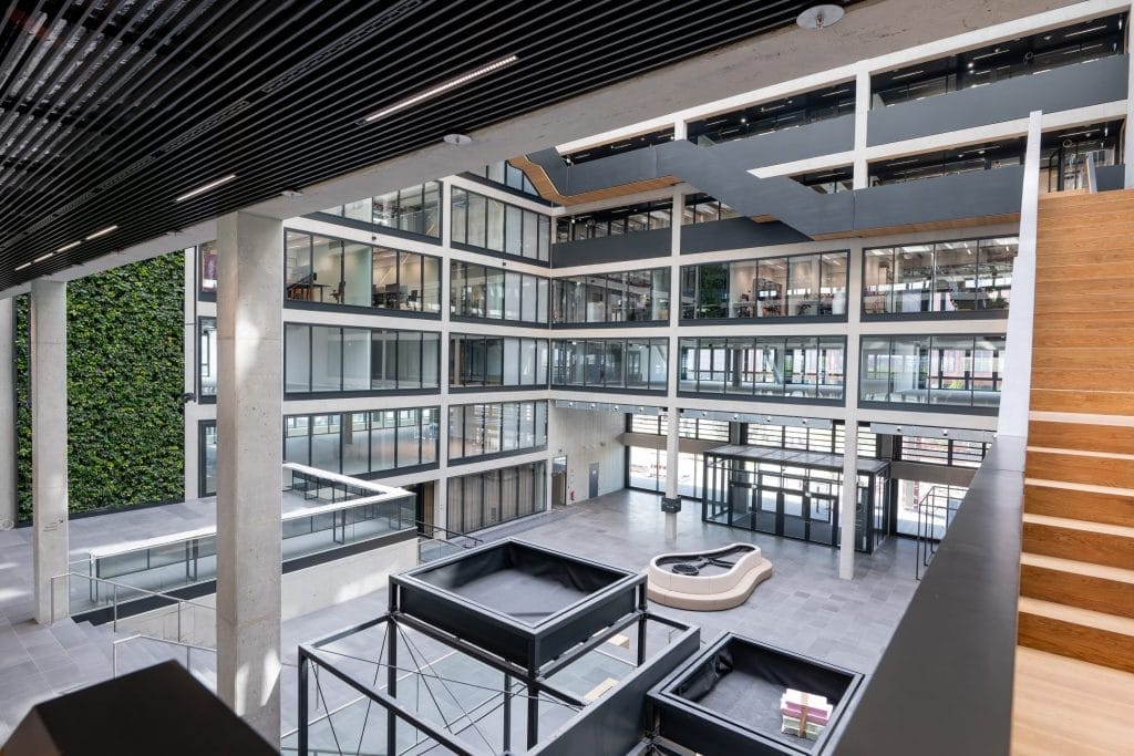 Moderne nachhaltige Büroeinrichtung mit natürlichem Licht und grüner Wand bei EDGE Workspaces.
